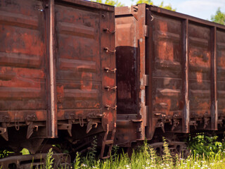 Old rusty railway gondola cars at the marshalling yard. Freight wagons close-up. Transportation of...