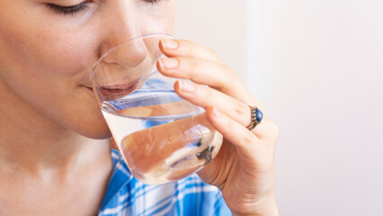 Woman drinking a fresh glass of water at home