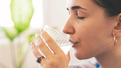 Woman drinking a fresh glass of water at home