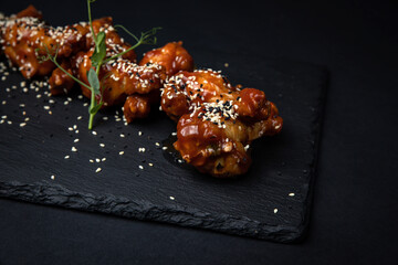 grilled chicken wings with sesame seeds and spices on black background