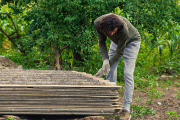 Risks nonProfessionals unprotected remove sheets of asbestos material from the roof of a rural home House with old, danger