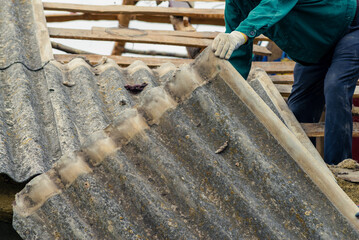 Risks nonProfessionals unprotected remove sheets of asbestos material from the roof of a rural home House with old, danger