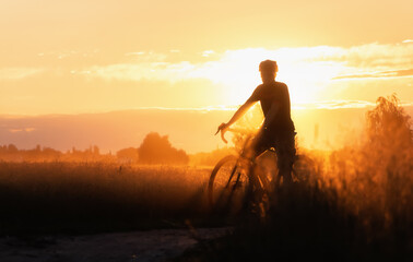 Silhouette of Cyclist on a countryside dirt road at sunset.
