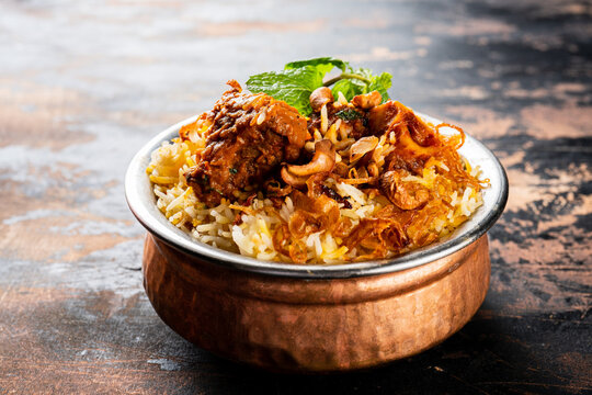 Mutton Biryani served in a golden dish isolated on dark background side view indian food