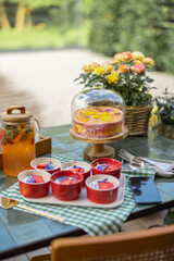 Festively served dinner table with sweet cakes and flowers at backyard during summer time