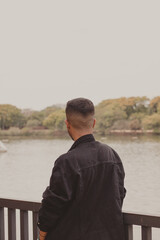 Fototapeta premium young man standing backwards looking at the lake view