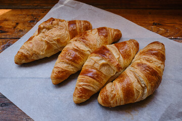 Ready crispy croissant on parchment paper. Fresh homemade cakes. Delicious traditional french crispy croissants for breakfast