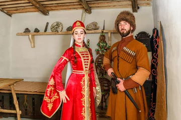 Fotobehang A young couple a man and a girl in Caucasian Circassian national costumes stand inside their traditional old house in the village © PORTFOLIO studio