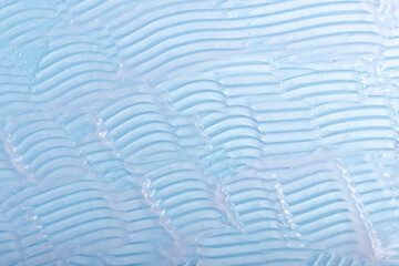 Fototapeta premium Abstract patterns of transparent moisturizing facial gel. The texture of the cosmetic product is smeared on a blue background.