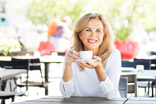 Eine attraktive, reife Frau trinkt einen Cappuccino in einem Café 