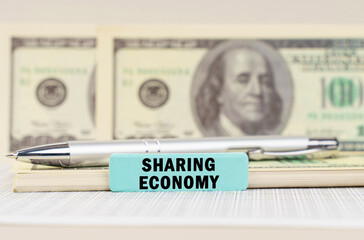 On the dollars are a pen and a sign with the inscription - Sharing economy