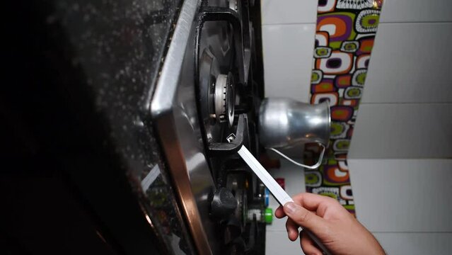 Vertical video of a hand lighting the stove withm an electric lighter