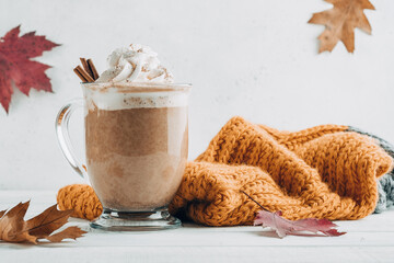 Pumpkin spice latte in a glass mug with cinnamon with Autumn decoration