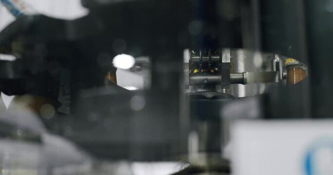 Capping process of full beer bottles. Machine for capping bottles. Factory, brewery concept. Beer bottles on automated machine during capping process. Video of beer bottles moving on a conveyor belt.