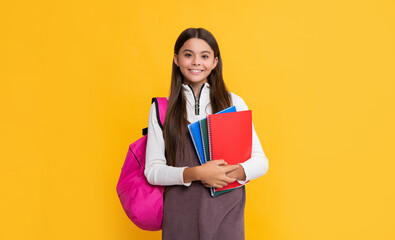 happy child with school backpack and planner on yellow background