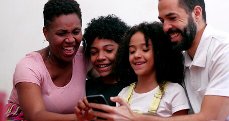 Obraz premium Interracial family using cellphone. Mixed race parents and children looking at smartphone device