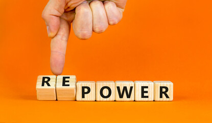 Power or repower symbol. Businessman turns wooden cubes and changes concept words Power to Repower. Beautiful orange table orange background. Business ecological power or repower concept. Copy space.