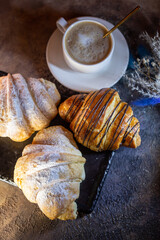 chocolate croissant and a cup of coffee on a blackboard top view