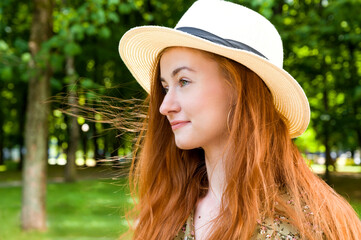 Side view summer portrait with happy smiling female wearing summer hat and dress.