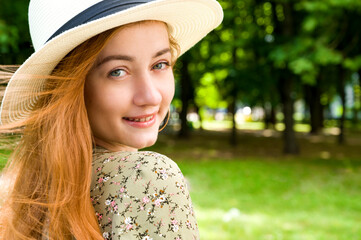 Closeup summer portrait of a young red haired girl in a dress and wearing hat.Banner with place for...