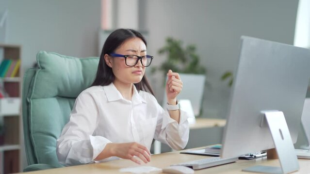 Sick young asian businesswoman coughing in office workplace. Employee entrepreneur worker indoor feeling unwell have a sore throat and chest. Unhealthy business female working on computer at desk