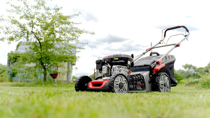 Fototapeta na wymiar Lawn mover on green grass in modern garden. Machine for cutting lawns.
