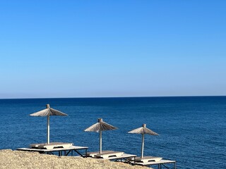 Beach with umbrellas and sunbeds against blue sea and sky at sunny summer day.