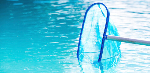 Obraz premium Cleaning a swimming pool with a metal frame with a net from leaves and dirt. Pool cleaner during work. Solar banner. The concept of summer holidays.