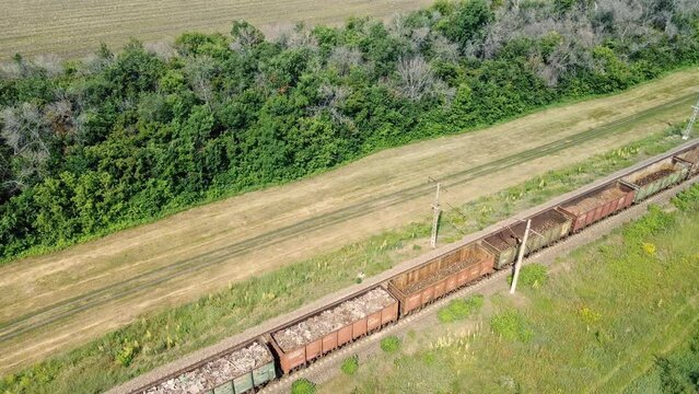 Cargo train transporting bulk wagons across rural, logistic concept. Aerial view