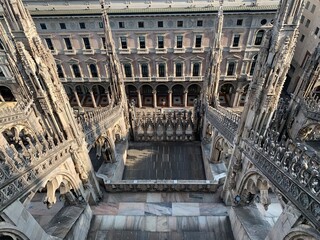 Facade, exterior of Galleria Vittorio Emanuelle II shopping mall and Pizza del Duomo square. View from Duomo di Milano church rooftop. Gothic, Renessaince style decorations. Milan, Lombardy, Italy