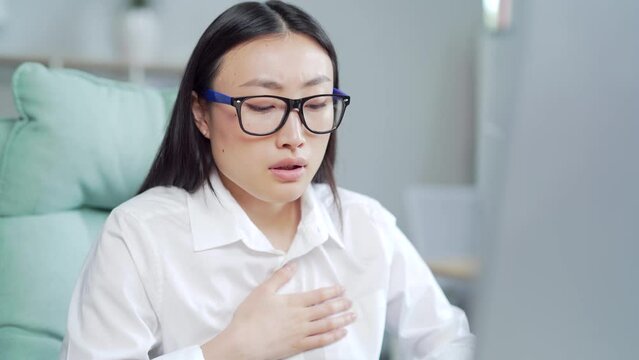 young asian female office worker having panic attack at workplace. business woman employee in the office shortness of breath, tired and sick having severe chest pain heartache at work indoor. Asia