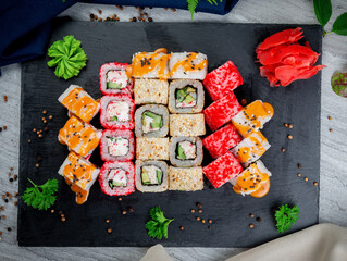 Set with fried and baked rolls, sushi on a stone board on a light table