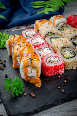 Set with fried and baked rolls, sushi on a stone board on a light table