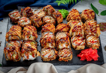 Set with fried and baked rolls, sushi on a stone board on a light table