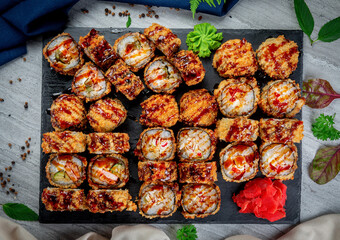 Set with fried and baked rolls, sushi on a stone board on a light table