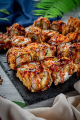 Set with fried and baked rolls, sushi on a stone board on a light table