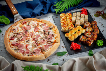 Ham and mushroom pizza on shovel and roasted and baked set with sushi and rolls. Freshly baked with parmesan, creamy sauce