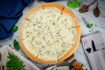 Four cheese pizza on a shovel. Freshly baked with cream sauce, parmesan, gouda, mozzarella and dor blue