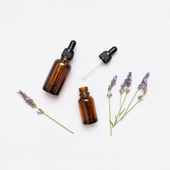Brown glass bottles with pipette with lavender essence oil, lavender flowers on white background top view. Natural cosmetics with lavender extract, aromatherapy, spa, body care, mock up