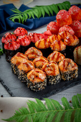 Set with fried and baked rolls, sushi on a stone board on a light table