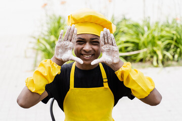 Black african cook teenager showing hands with flour and smiling. African child in chefs hat and...