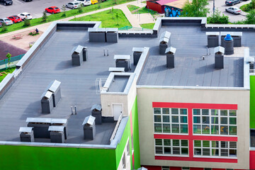 Top view dark flat roof with air conditioners and hydro insulation membranes modern school building...