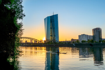 Europäische Zentralbank mit Frankfurter Skyline im Sonnenuntergang

