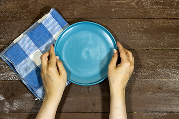 hand holding an empty ceramic blue plate on wood table