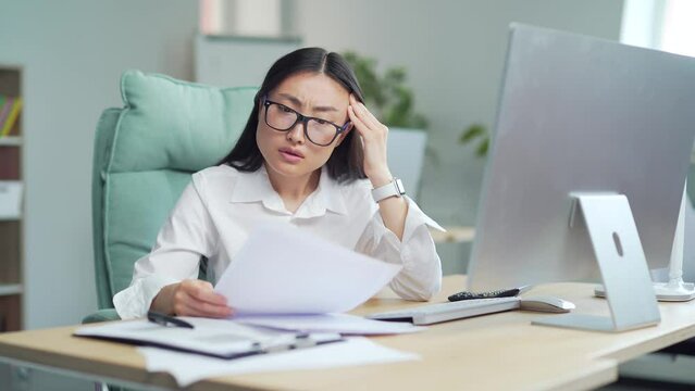 Difficult asian woman employee to deal with paperwork. documents. Stressed pensive businesswoman confused by mistake, thinking, looking papers. bookkeeper, booker vaguely, dimly at work in office