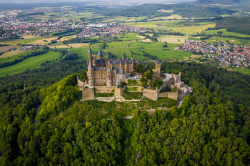 Drone shot of Hohenzollern Castle on forested mountain top in the Swabian Alps in summer. Scenic aerial view of old German Burg. Famous fairytale Gothic landmark in Stuttgart vicinity