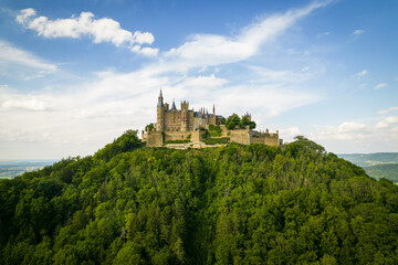 Fototapeta na wymiar Drone shot of Hohenzollern Castle on forested mountain top in the Swabian Alps in summer. Scenic aerial view of old German Burg. Famous fairytale Gothic landmark in Stuttgart vicinity