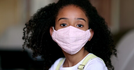 Little girl wearing covid-19 face mask. Portrait kid putting mask on