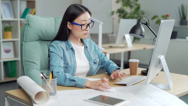 young creative asian woman modern designer or architect sitting at desk pc computer laptop in office workplace. makes a draft drawing. Work with interior or house design projects sketch on desktop