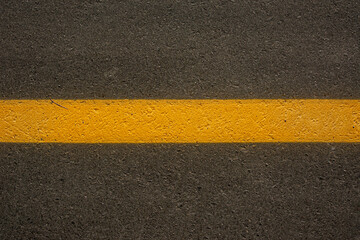 Solid painted yellow line marks the rough texture of asphalt